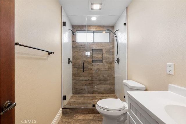 full bathroom with a stall shower, wood finished floors, vanity, baseboards, and toilet