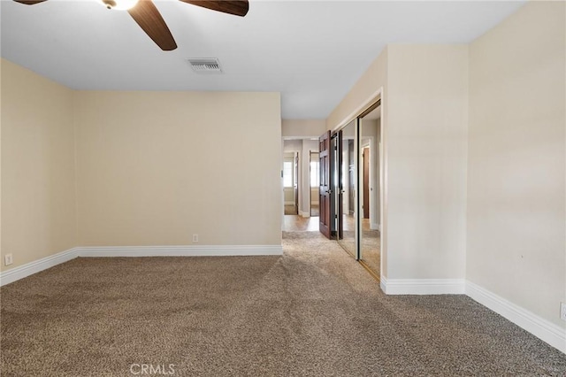 unfurnished room featuring visible vents, a ceiling fan, baseboards, and carpet floors
