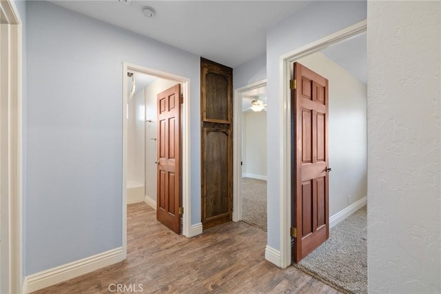 hall with baseboards and wood finished floors