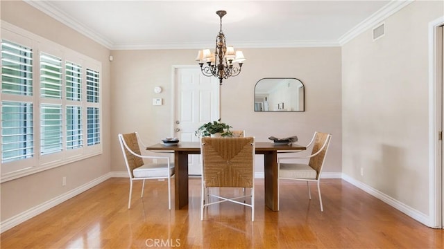 dining space featuring light wood-style floors, baseboards, visible vents, and a chandelier