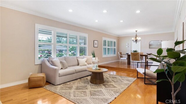 living area with an inviting chandelier, crown molding, baseboards, recessed lighting, and light wood finished floors
