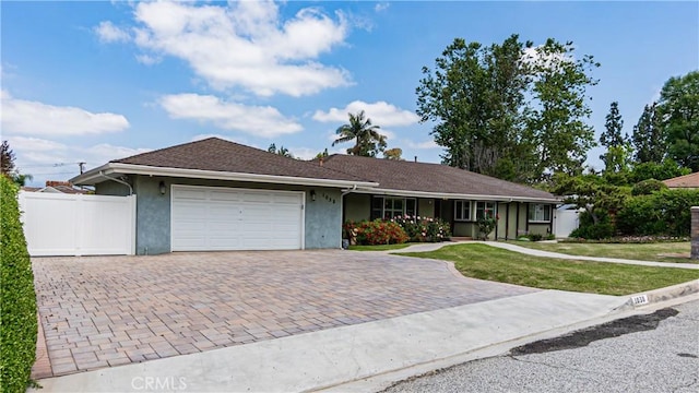 ranch-style home with a garage, stucco siding, decorative driveway, and a front yard