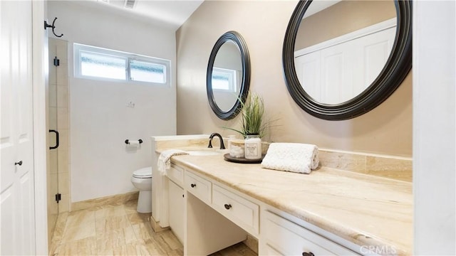 bathroom with vanity, a shower with door, and toilet