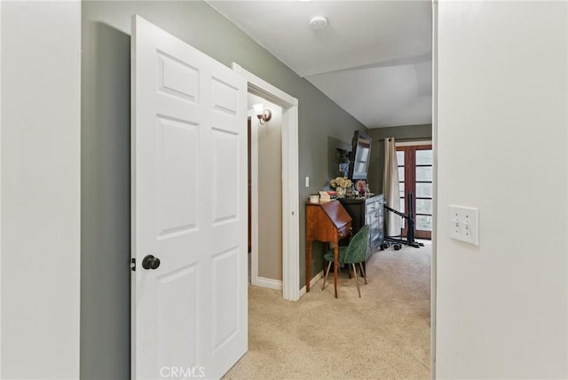 hallway with baseboards and light colored carpet
