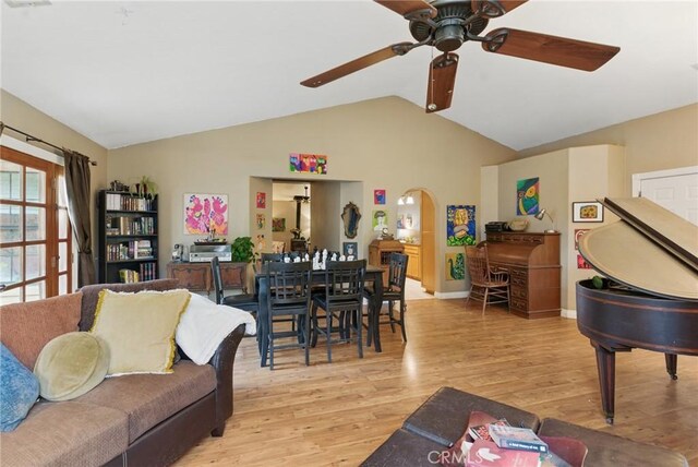 living area with a ceiling fan, arched walkways, light wood-style flooring, and lofted ceiling