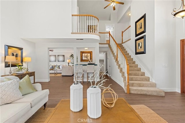 living room featuring stairway, a high ceiling, and wood finished floors