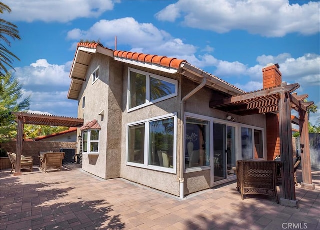 back of property with a patio, stucco siding, a pergola, and fence