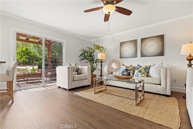 living area with crown molding, a ceiling fan, and wood finished floors