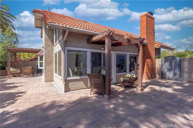 rear view of property with a patio, a pergola, a gate, and stucco siding