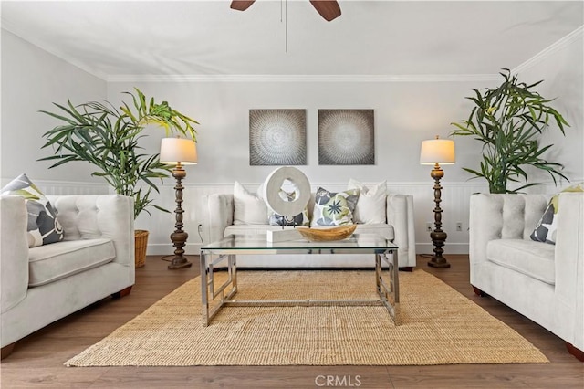 living room featuring crown molding, ceiling fan, wood finished floors, and a wainscoted wall