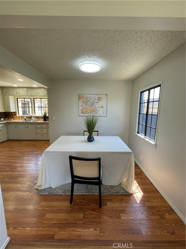 dining area with baseboards, a textured ceiling, and wood finished floors