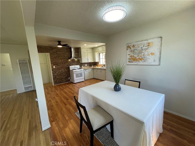dining room with a heating unit, a textured ceiling, ceiling fan, and wood finished floors