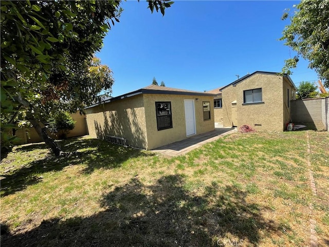 back of property with a lawn, stucco siding, and fence