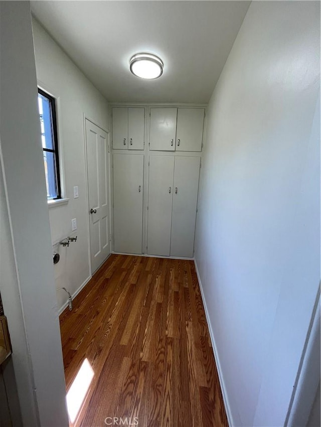corridor with baseboards and dark wood-type flooring