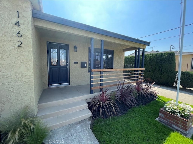 property entrance featuring a porch and stucco siding