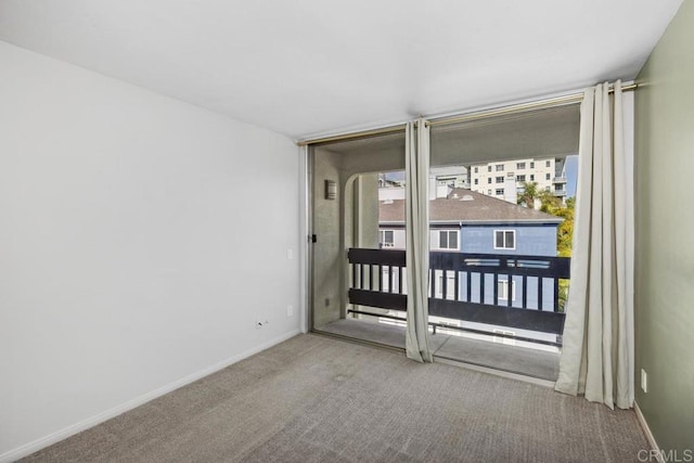 carpeted spare room featuring baseboards and expansive windows