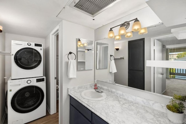 bathroom with visible vents, stacked washer / drying machine, toilet, and vanity