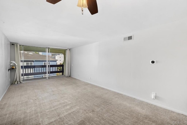empty room with carpet flooring, a ceiling fan, baseboards, and visible vents