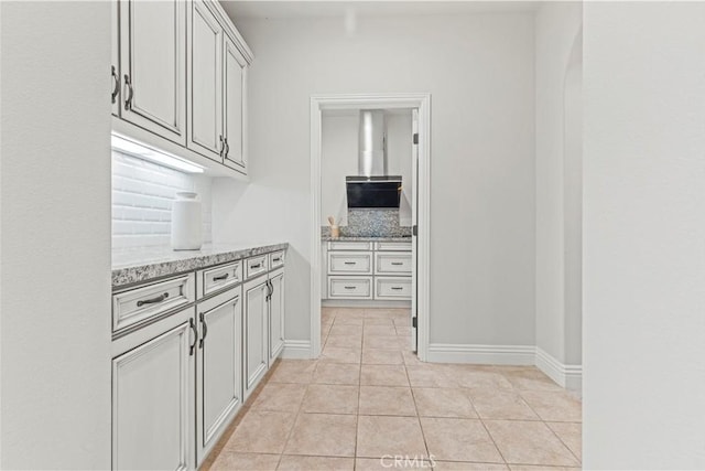 kitchen with light tile patterned flooring, baseboards, and light stone counters