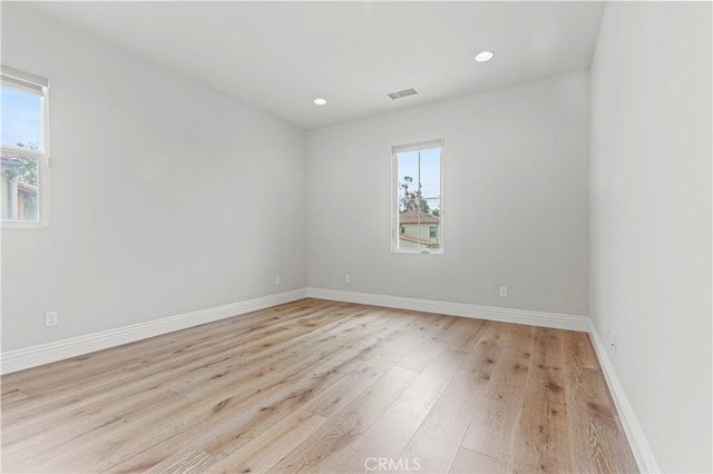 spare room with light wood-style floors, baseboards, and visible vents