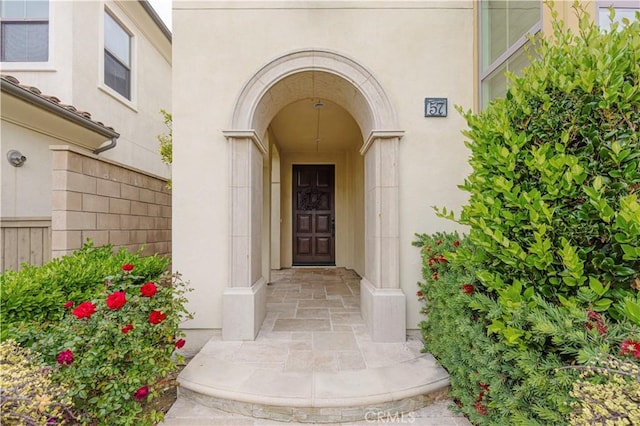 doorway to property with fence and stucco siding
