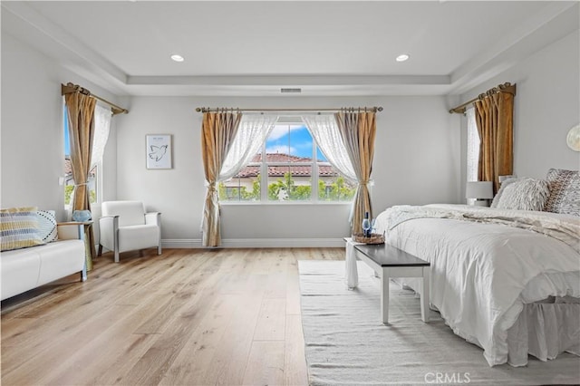 bedroom with recessed lighting, a raised ceiling, light wood finished floors, and baseboards