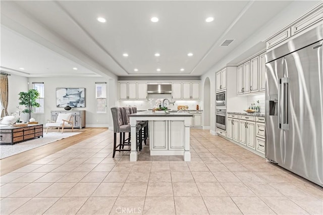 kitchen with stainless steel appliances, open floor plan, decorative backsplash, under cabinet range hood, and visible vents