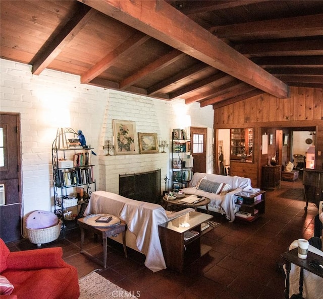 living area with a fireplace, lofted ceiling with beams, wood walls, and a wealth of natural light