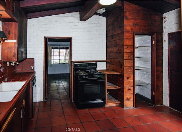 kitchen featuring lofted ceiling with beams, a sink, black range with gas cooktop, tile countertops, and dark tile patterned floors