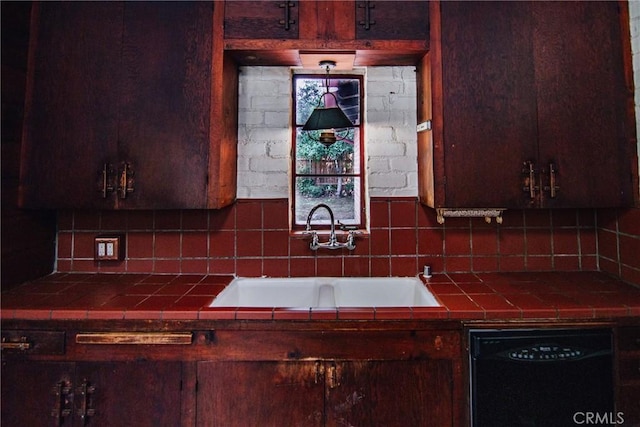 kitchen featuring a sink, tile counters, backsplash, and black dishwasher