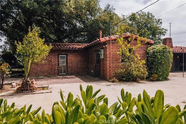 back of house with a tiled roof and brick siding
