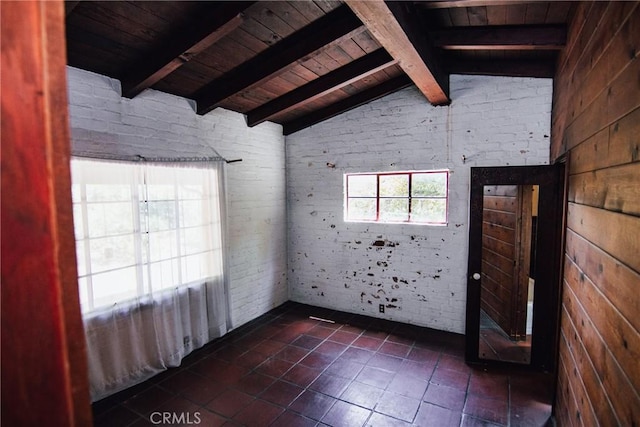 spare room with dark tile patterned floors, lofted ceiling with beams, wood ceiling, and brick wall