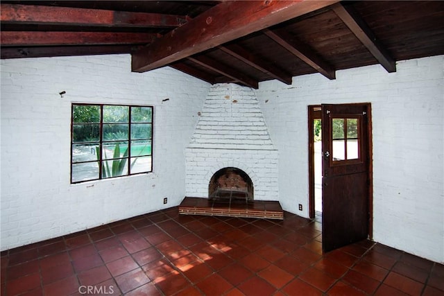 unfurnished living room featuring wooden ceiling, dark tile patterned floors, vaulted ceiling with beams, and brick wall