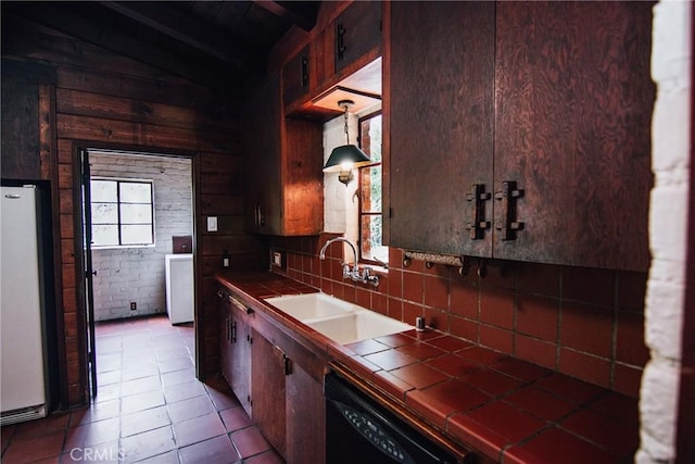 kitchen featuring plenty of natural light, tile counters, freestanding refrigerator, and black dishwasher