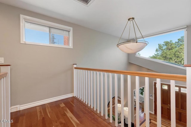staircase featuring baseboards, wood finished floors, and visible vents
