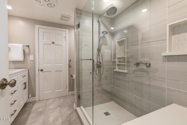 bathroom featuring vanity, tile patterned floors, a tile shower, and visible vents