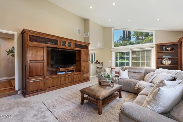 living area featuring high vaulted ceiling, visible vents, and light carpet
