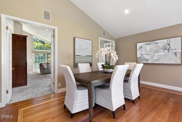 dining room with high vaulted ceiling, visible vents, baseboards, and light wood-type flooring