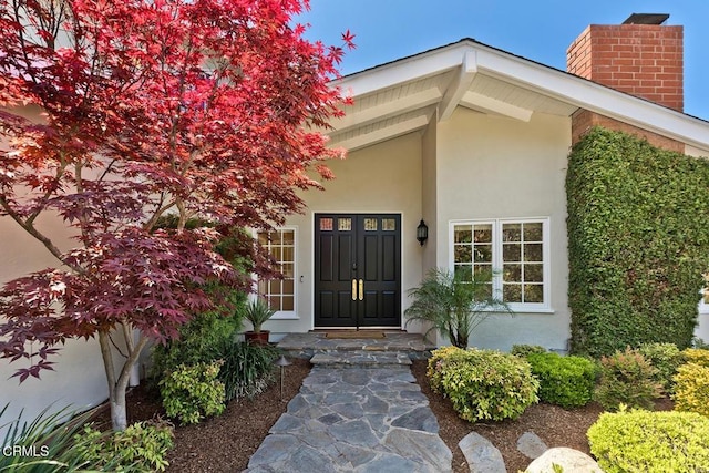 doorway to property with a chimney and stucco siding