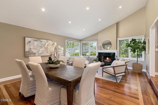 dining space with a fireplace, high vaulted ceiling, baseboards, light wood-style floors, and recessed lighting