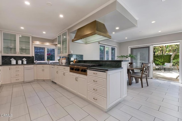 kitchen featuring stainless steel gas stovetop, dark countertops, range hood, and a wealth of natural light