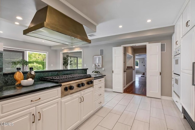 kitchen with white cabinets, island range hood, dark countertops, and stainless steel gas stovetop