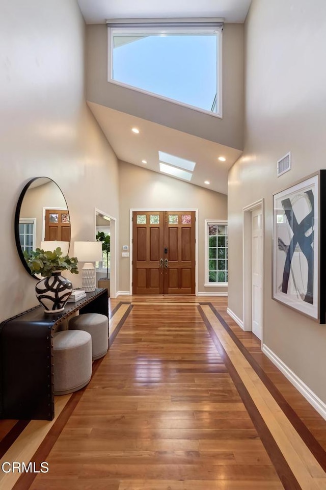 foyer with a high ceiling, visible vents, baseboards, and light wood finished floors
