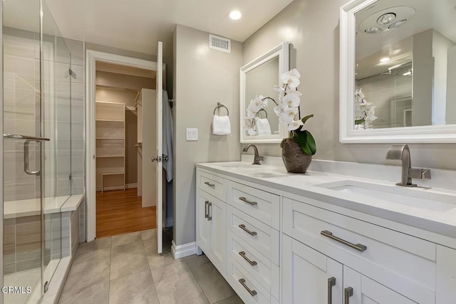 bathroom with a sink, a shower stall, and visible vents