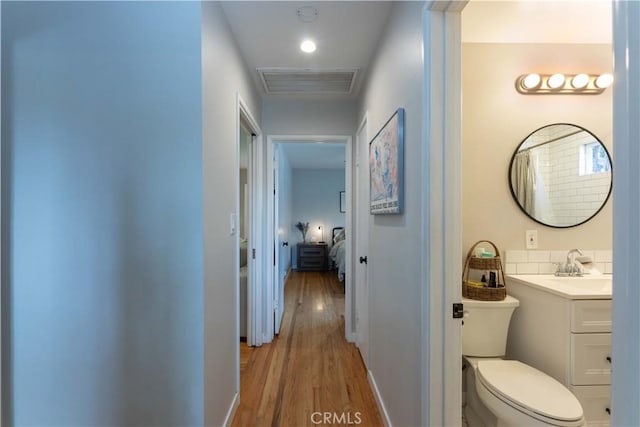 bathroom with visible vents, vanity, wood finished floors, toilet, and baseboards