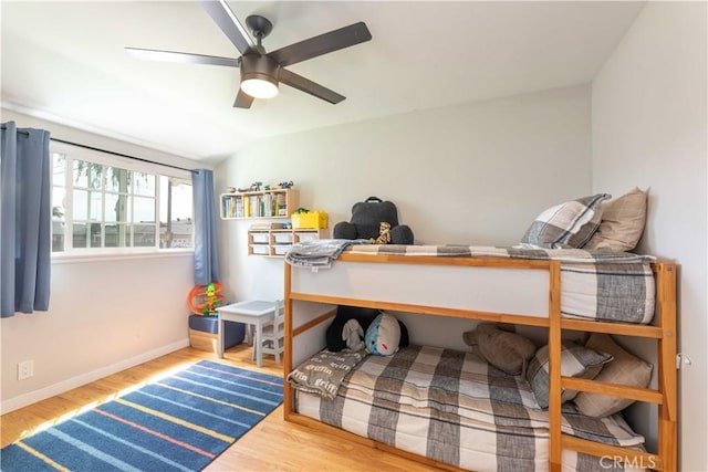 bedroom with baseboards, ceiling fan, wood finished floors, and lofted ceiling