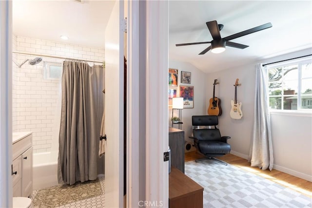 bathroom featuring ceiling fan, vanity, wood finished floors, lofted ceiling, and shower / tub combo