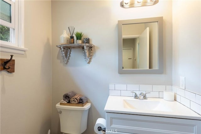 half bathroom featuring vanity, tasteful backsplash, and toilet