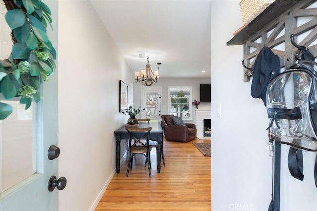 foyer featuring a fireplace, baseboards, an inviting chandelier, recessed lighting, and light wood-style flooring