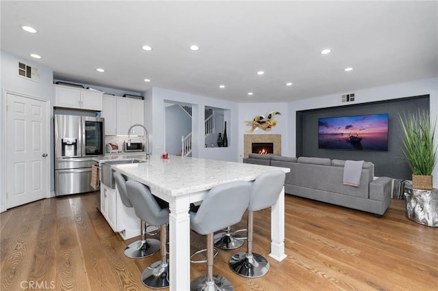 kitchen featuring stainless steel fridge with ice dispenser, recessed lighting, and visible vents